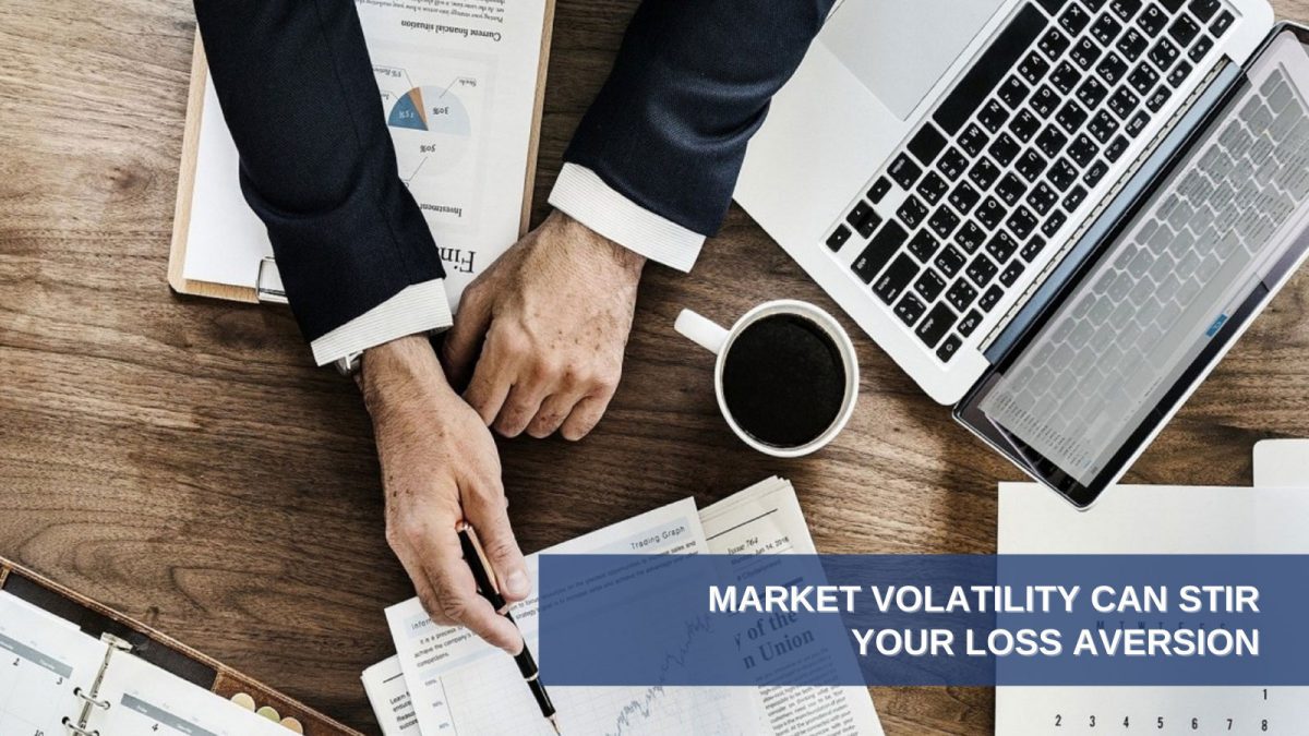Market Volatility Can Stir Your Loss Aversion, camera looking down on desktop with papers, computer, coffee and man's hands